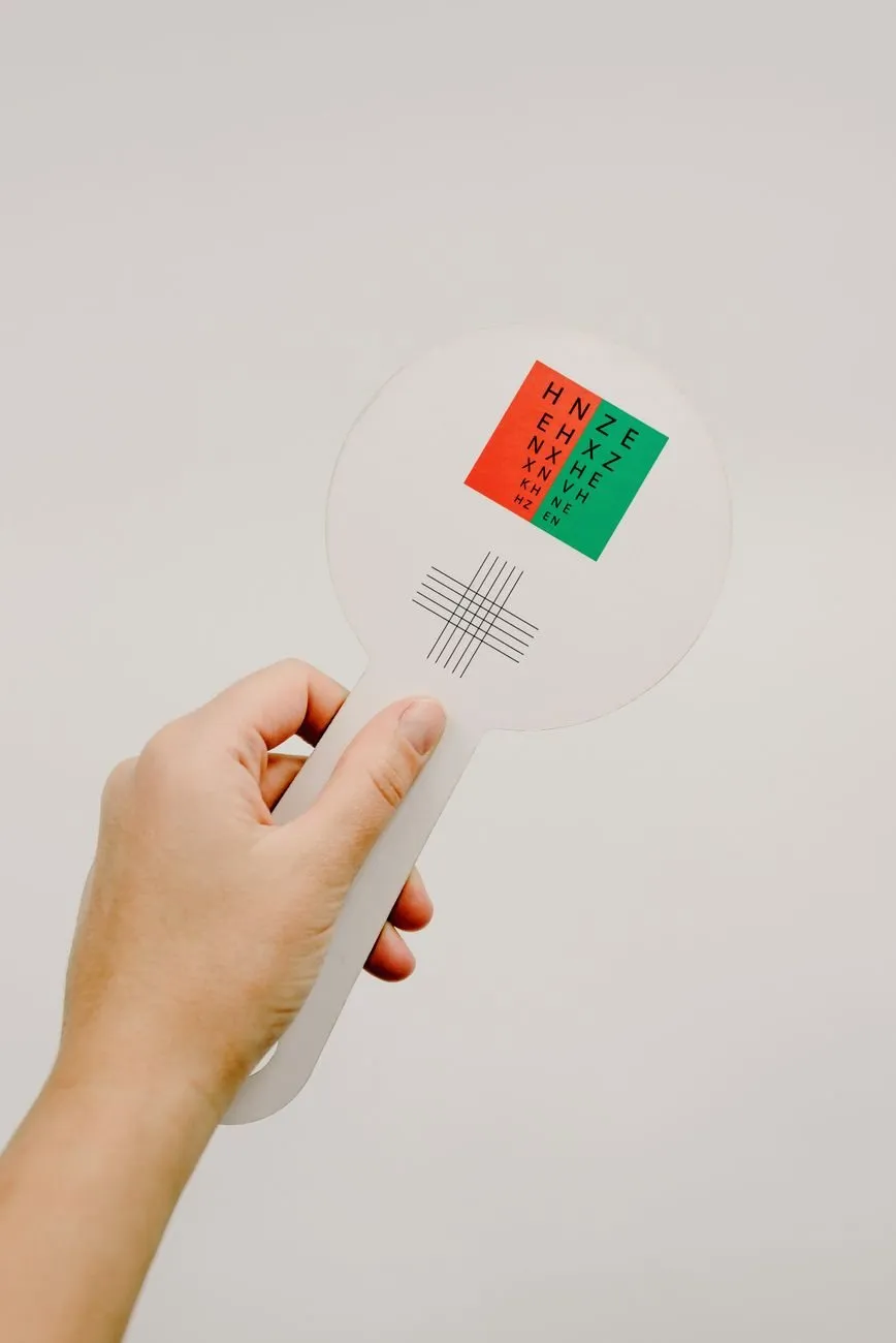 A hand holding up a red and green test card with a cross target below it