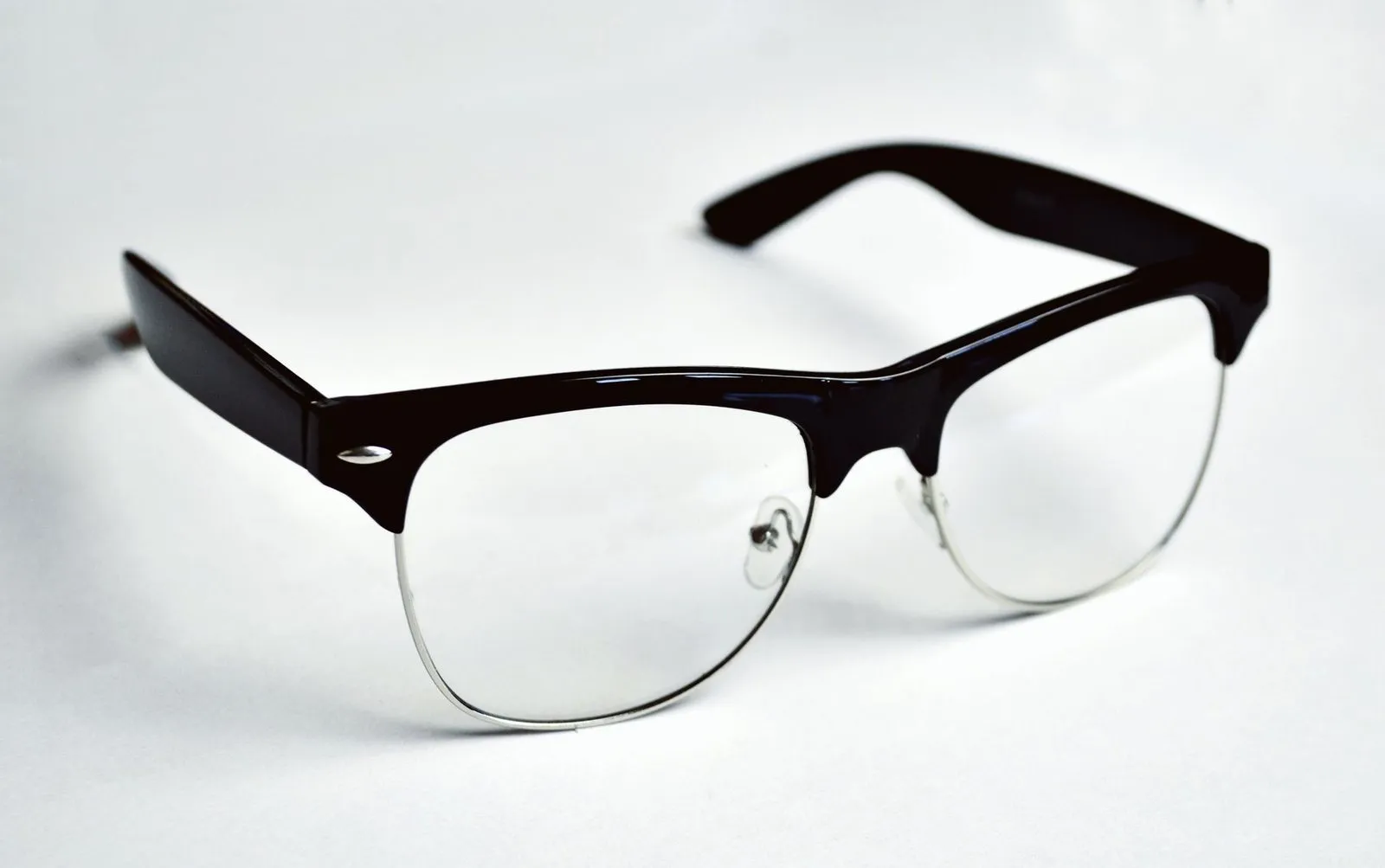 Black browline glasses with thin silver lower rims on a white background