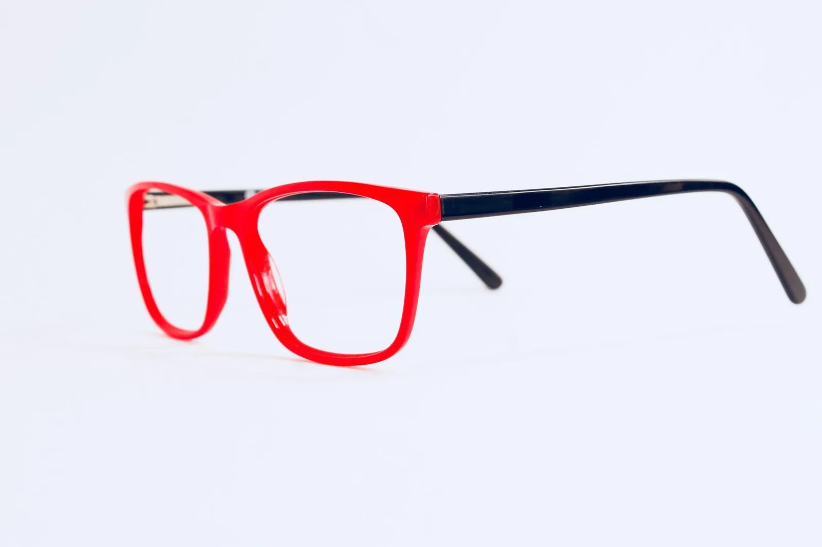 Bright red rectangular glasses with navy arms on a pale background