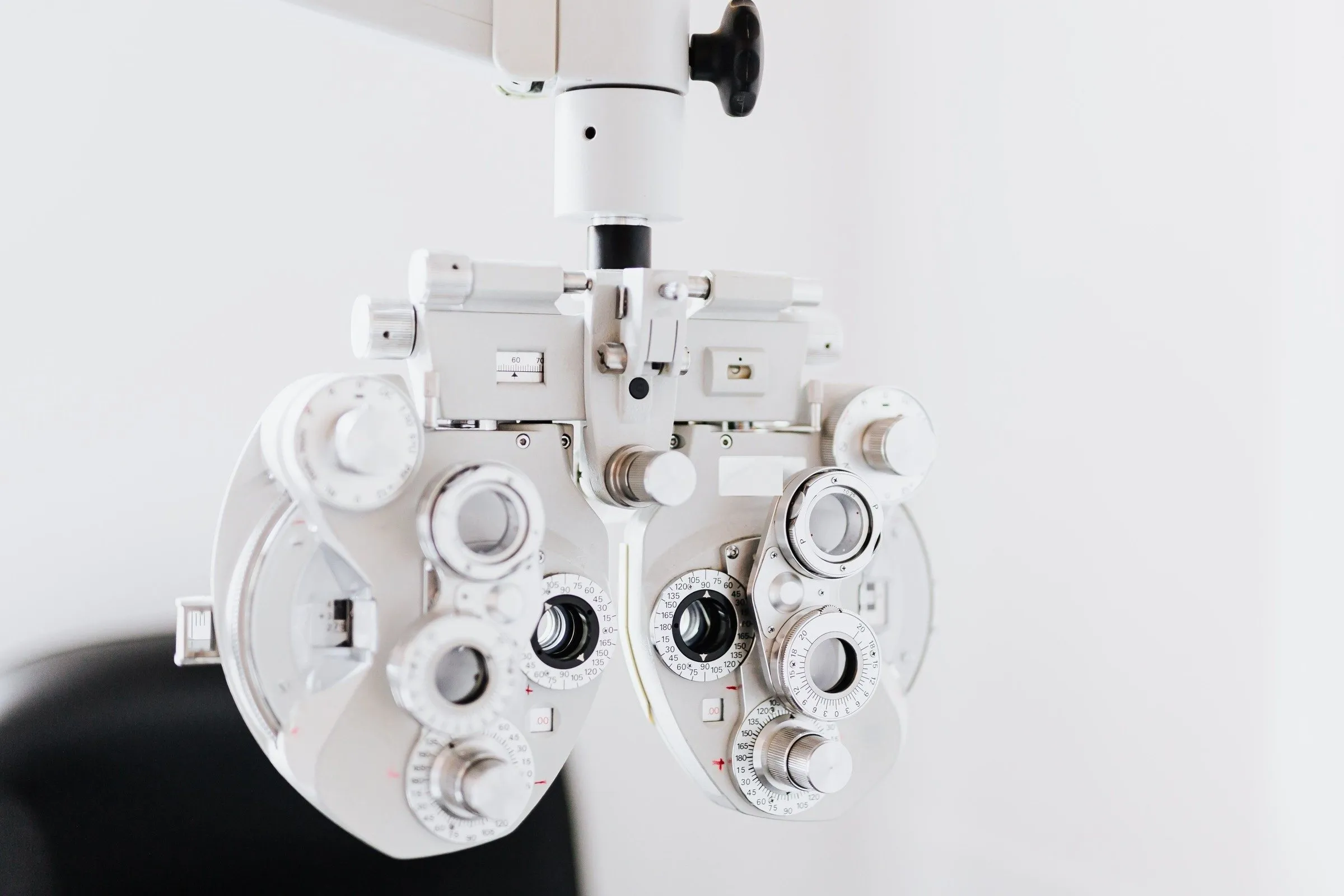 A white phoropter, the instrument used to find your prescription, in a bright consulting room