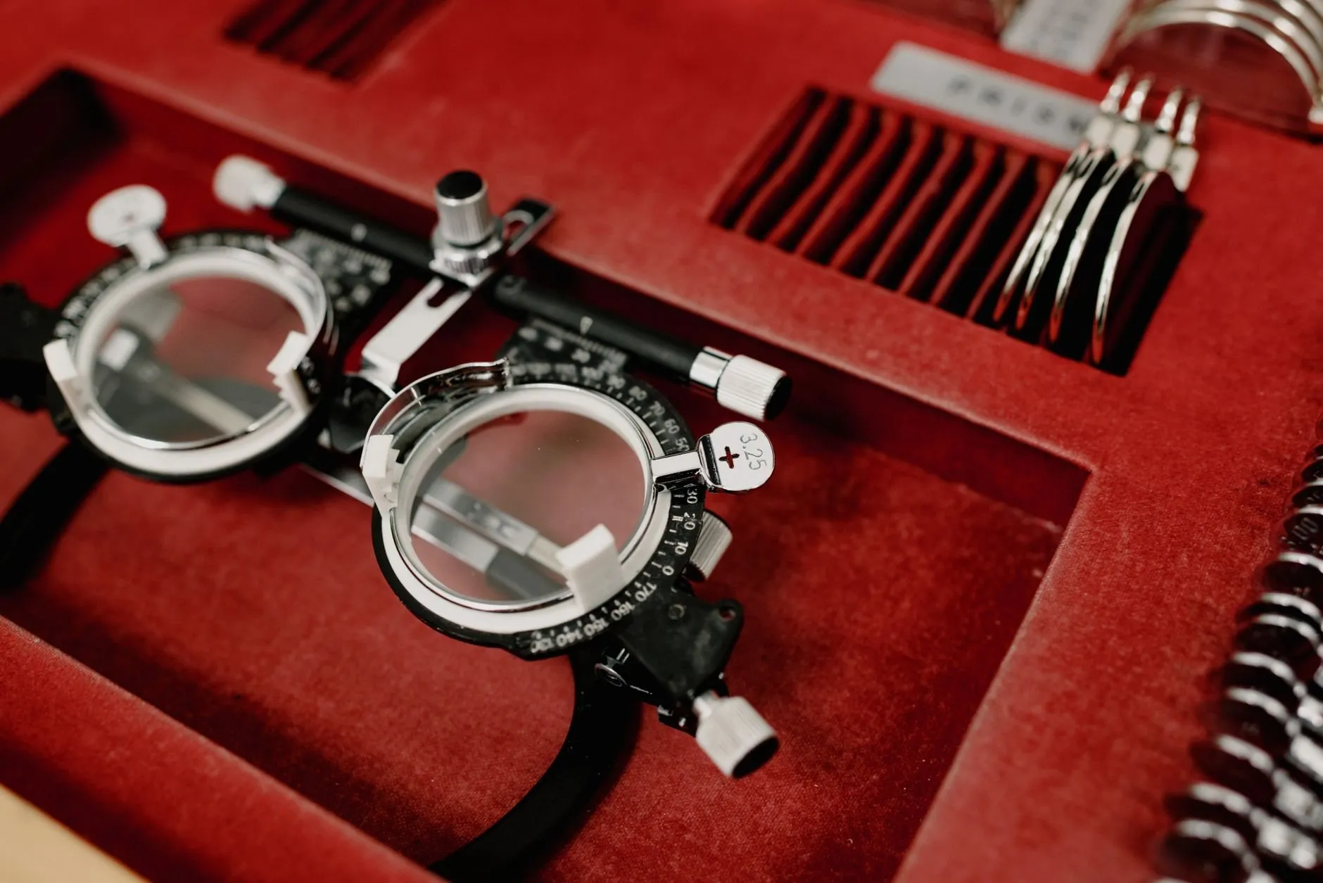 A trial frame with lens holders resting in a red velvet case of test lenses