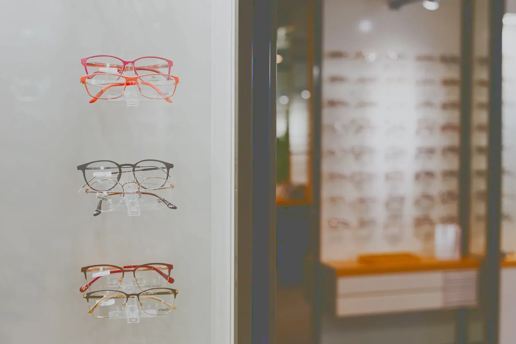 A dispensing wall of spectacle frames on a lit rack